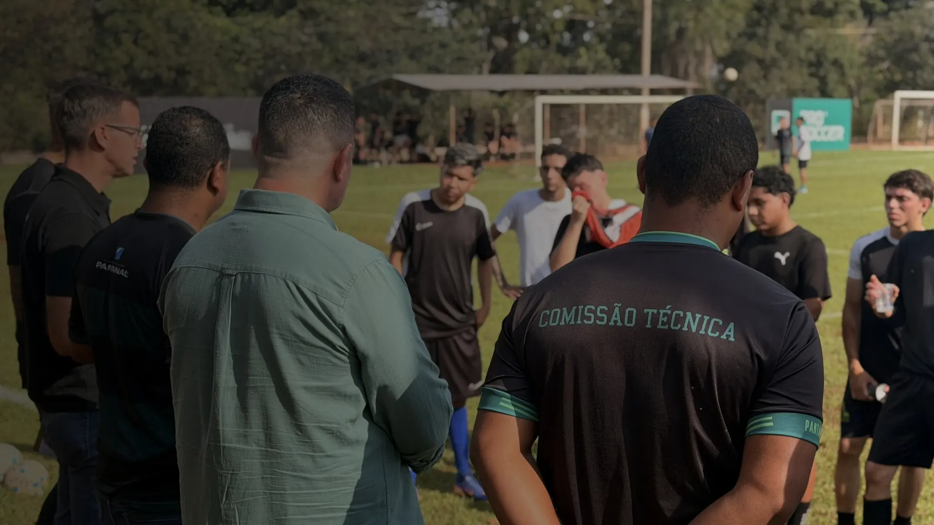 Grupo reunido em volta da comissão técnica no gramado